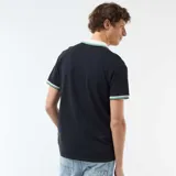 Remera de piqué de algodón color azul marino, con cuello polo en contraste color crema y detalles de rayas verdes y blancas en el cuello y los puños.