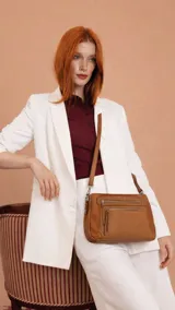 Bandolera de tamaño mediano confeccionada en símil cuero con detalles en nobuck. Presenta un diseño rectangular con cierre principal, bolsillos frontales con cierre y correa larga ajustable para llevar al hombro o cruzada.