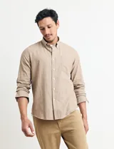 Camisa de manga larga confeccionada en una mezcla de algodón y lino, con cuello abotonado, bolsillo frontal en el pecho y cierre de botones.