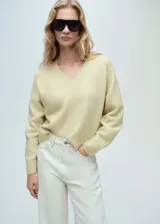 Jersey de punto color amarillo claro, con cuello en pico y diseño recto de manga larga con puños acanalados.