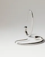 Aros colgantes Pdpaola modelo Eira en plata de ley, con diseño abierto de líneas curvas y acabado pulido.