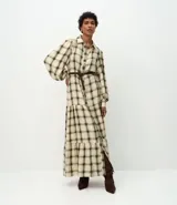 Vestido largo de corte midi, confeccionado en tejido de viscosa con estampado de cuadros. Presenta cuello camisero, cierre frontal abotonado, mangas largas abullonadas y falda con volados. Incluye un cinturón fino para ajustar a la cintura.