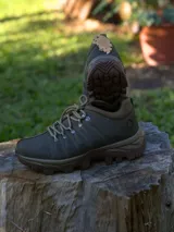 Calzado de trekking color verde oliva con suela de goma marrón de alto agarre. Presenta cordones reforzados, ojales metálicos y diseño robusto ideal para actividades al aire libre.