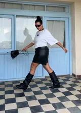 Bota de caña alta estilo slouchy color negro, con diseño de cuatro correas horizontales con hebillas metálicas doradas y punta redondeada.