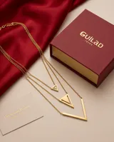 Collar de triple cadena de acero con baño de oro, compuesto por tres dijes geométricos en forma de V de diferentes tamaños.
