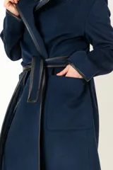 Tapado azul marino de lana y cashmere, con cuello solapa, bolsillos delanteros y cinturón de cuero negro.