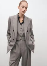 Blazer de doble botonadura color gris, con solapas de muesca, bolsillos con solapa en el frente y forro interior.