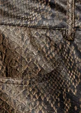 Pantalón de tiro medio con diseño recto y largo, confeccionado en material con efecto piel de serpiente. Cuenta con cierre delantero de cremallera y botón, trabillas para cinturón y bolsillos laterales.