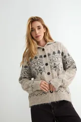 Saco de punto con cuello tipo polo, cierre frontal de botones oscuros y diseño de estampado jacquard en tonos grises y beige. Presenta mangas largas con puños acanalados y textura suave.