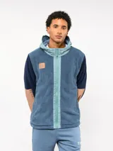 Campera de polar con capucha, cierre frontal completo y diseño en bloques de color azul y azul marino. Presenta detalles en nylon en la zona del cierre y la capucha, con logo de la marca aplicado en el pecho.