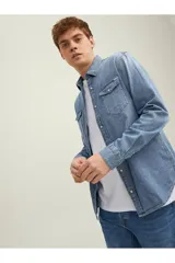 Camisa de denim celeste de manga larga, con cuello clásico, cierre frontal con botones a presión y dos bolsillos con solapa abotonada en el pecho.