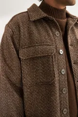 Camisa estilo leñadora marrón con diseño de espiga, cuello clásico, abrochadura frontal a la vista, bolsillos plaqué con tapa en el pecho, mangas largas con puño y botón.