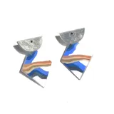 Par de aros colgantes con forma geométrica. La parte superior es un semicírculo plateado con glitter, y la parte inferior es un rombo blanco con franjas horizontales en tonos azul, marrón y gris.