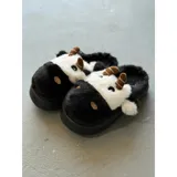 Pantuflas de peluche con diseño de vaca, confeccionadas en piel sintética suave. Cuentan con suela de goma antideslizante y diseño abierto en el talón.