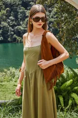 Bolso tipo hobo de gamuza color marrón, con diseño de flecos en los laterales y correa integrada al cuerpo del bolso.