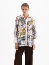 Camisa de manga larga confeccionada en poplín de encaje con diseño de cuadrados y estampado floral multicolor. Presenta cuello clásico, cartera oculta con botones, bolsillos plaque en el frente y puños anchos en color blanco liso.