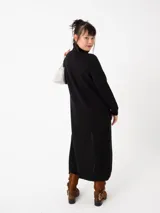 Buzo largo gris de tejido de punto grueso con cuello alto y capucha con orejas de conejo rojas. Tiene mangas largas y un tajo lateral.