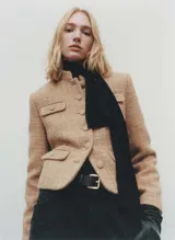 Chaqueta de corte recto confeccionada en tejido tweed con mezcla de lana. Presenta cuello de tira, cierre frontal con botones, manga larga y cuatro bolsillos delanteros con solapa y botón. Incluye forro interior.