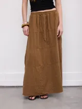 Falda larga marrón, de corte evasé con detalles de costuras horizontales y diseño fluido.