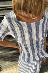 Remera de algodón con diseño fruncido en el frente y mangas cortas, con estampado de rayas verticales en azul y blanco.