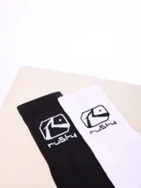 Par de medias altas Rusty, una en color blanco y otra en color negro, con el logo de la marca estampado en la parte superior.