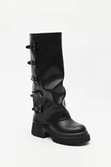 Bota de caña alta estilo biker, color negro, con plataforma robusta y suela dentada. Presenta múltiples tiras laterales con hebillas metálicas ajustables.