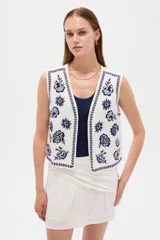 Chaleco sin mangas de algodón color blanco, con escote en V y bordados florales en azul marino.