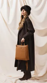 Mochila de diseño moderno y funcional, confeccionada en símil cuero con textura granulada. Cuenta con un bolsillo frontal con broche, cierre principal superior, manija superior y correas ajustables. Incluye logo de la marca grabado en el frente.
