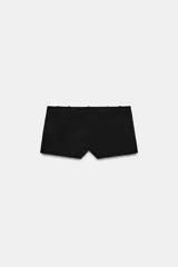 Shorts negros de tiro bajo, corte ajustado y muy corto, con bolsillos delanteros y cierre frontal con cremallera y gancho metálico.