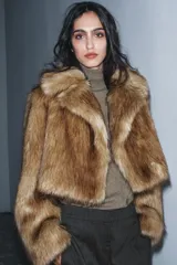 Chaqueta corta de pelo sintético color marrón claro, con cuello solapa y manga larga.