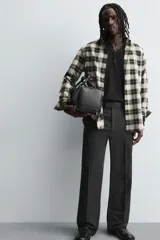 Bolso tipo bowling color negro con textura geométrica en relieve. Tiene doble asa de mano y correa de hombro ajustable y extraíble. El compartimento principal tiene cierre de cremallera y un bolsillo interior con cremallera.