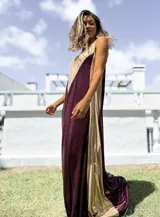 Vestido largo de corte holgado con diseño bicolor en tonos bordó y dorado, confeccionado en tela satinada con acabado brillante. Presenta escote en V y breteles anchos.