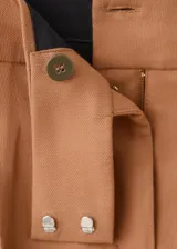 Short tipo falda pantalón de tiro bajo, color tostado, con diseño de tablas y bolsillos laterales.