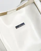 Cartera tipo tote de símil cuero blanco, con dos asas de mano y detalles de herrajes plateados en los laterales.