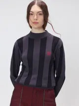 Sweater de punto con diseño de rayas verticales en tonos negro y gris oscuro. Presenta cuello alto tipo polera, mangas largas con puños ajustados y ruedo elástico. Incluye un pequeño bordado en color rojo en el pecho.