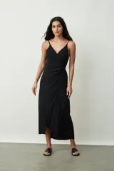 Vestido negro midi de tirantes finos, con escote cruzado en V y diseño envolvente con drapeado lateral que genera una abertura frontal.