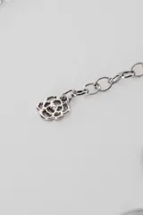 Cinturón plateado con eslabones de cadena y apliques circulares con diseño espiralado.