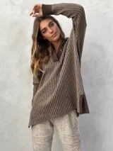 Sweater de punto color marrón con rayas verticales en un tono más claro, cuello en V y mangas largas. Presenta aberturas laterales en el dobladillo.