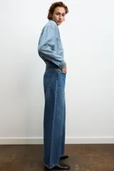 Jeans de tiro alto con diseño de pierna ancha y cinco bolsillos. Cuenta con cierre frontal mediante cremallera y botón metálico.