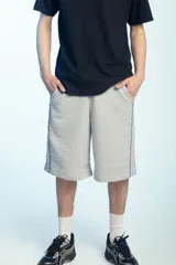 Bermuda deportiva de felpa color negro, de corte ancho y largo por debajo de las rodillas, con cintura elástica.