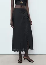 Falda midi recta de color negro, confeccionada en algodón con detalles bordados en el borde y cierre de cremallera lateral.