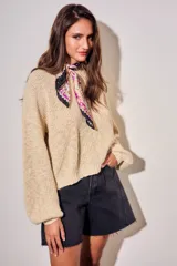 Sweater de tejido bouclé texturado color beige, con cuello redondo y mangas largas holgadas de corte amplio.