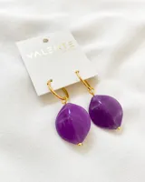 Aros colgantes con aro dorado y dije de resina color violeta con efecto marmolado.