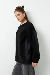 Buzo polar negro de manga larga y cuello redondo, con paneles de nylon en las mangas.