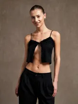 Top corto negro con breteles finos y detalle de volados en el escote.