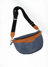 Riñonera azul con textura símil piel de cocodrilo, cierre metálico, correa de cuero color camel y correa de tela negra ajustable.