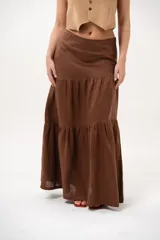 Pollera larga marrón de tiro medio, confeccionada en lino con diseño en niveles y vuelo.
