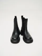 Bota tipo chelsea de cuero vacuno en color rojo con estampado floral grabado en negro. Presenta paneles laterales elásticos, suela de plataforma y taco cuadrado en color negro.