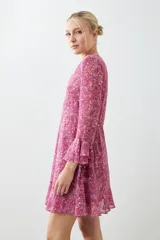 Vestido corto fucsia con estampado floral, escote en V, mangas largas con volados y falda acampanada con volados en el ruedo.