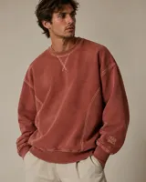 Buzo de cuello redondo color beige con diseño holgado, costuras en relieve y detalle de bordado en el puño.